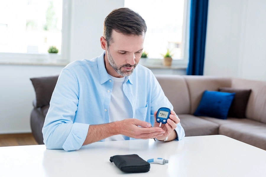 man in blue shirt checking blood sugar with glucometer